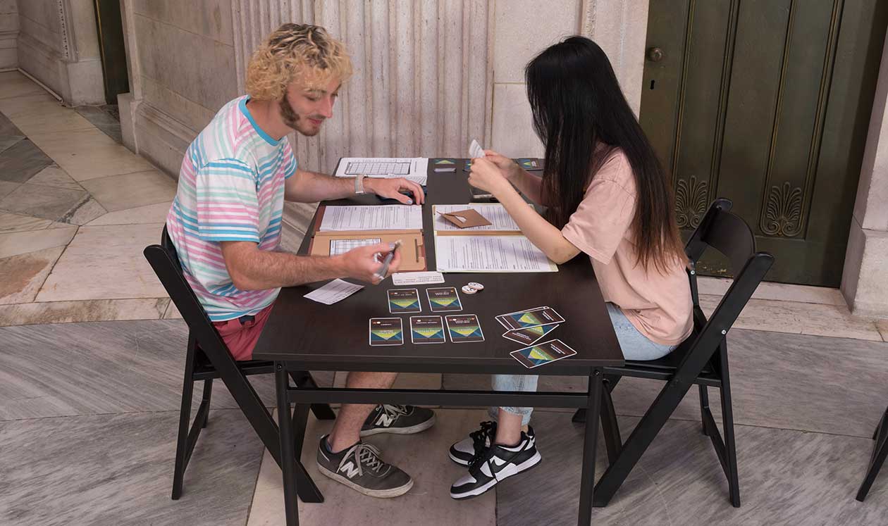 Two players sit at a table playing ___ vs. ___